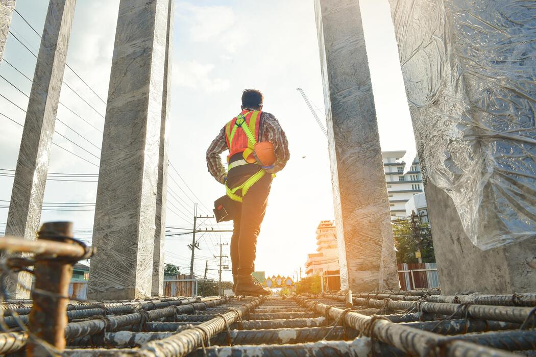 Construction engineer walking across reinforcement between concrete columns on a live site